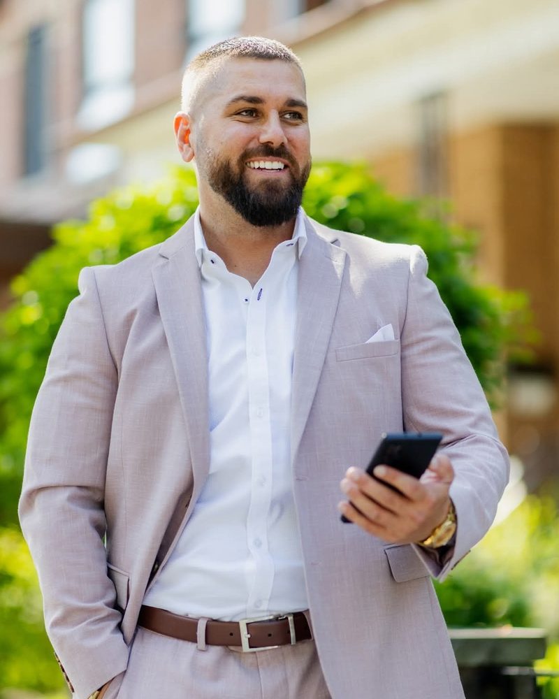 Jake Smith, Crypto Realtor Panama, in a light pink suit holding a phone